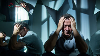 Мужчина сидит на полу среди разбитых зеркал